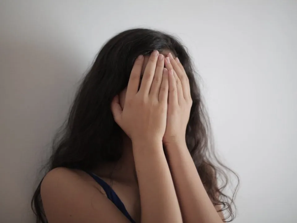 A woman covering her face with her hands. (Pexels/Andre Piacquadio)
