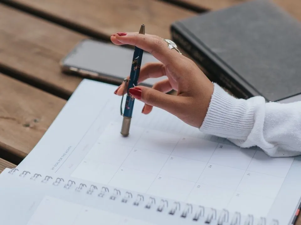 Someone fidgeting with a pen on a work planner. (Pexels/Anete Lusina)