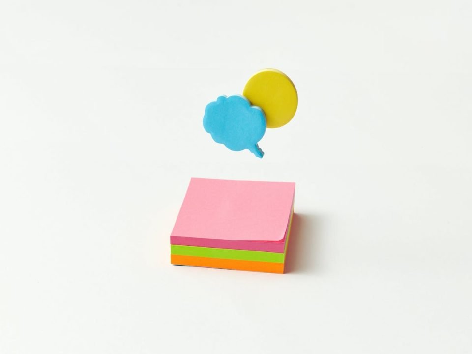 A stack of sticky notes below two speech-shaped pieces of paper (DS Stories on Pexels).
