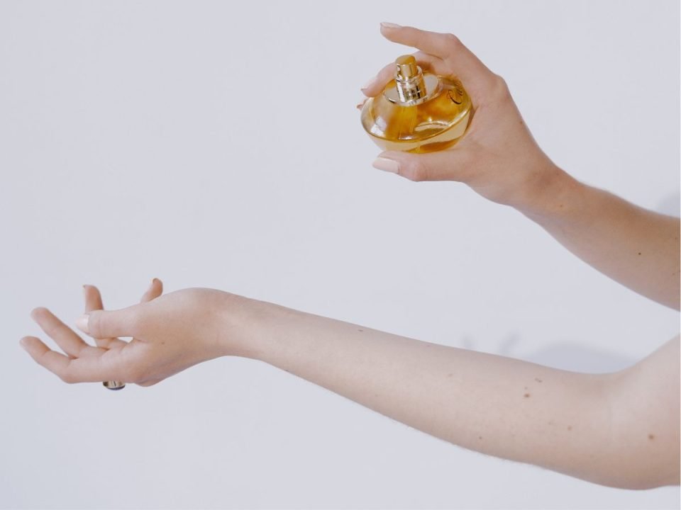 Someone prepares to spray fragrance on their wrist. Only their arms are in frame. (Canva)