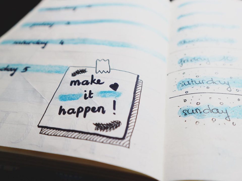A page in a planner with a doodle of a sticky note that says "Make it happen!"