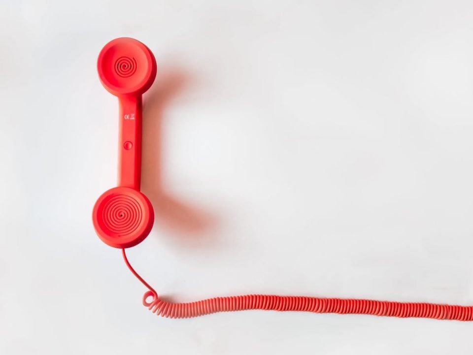 A red corded telephone on a white background.