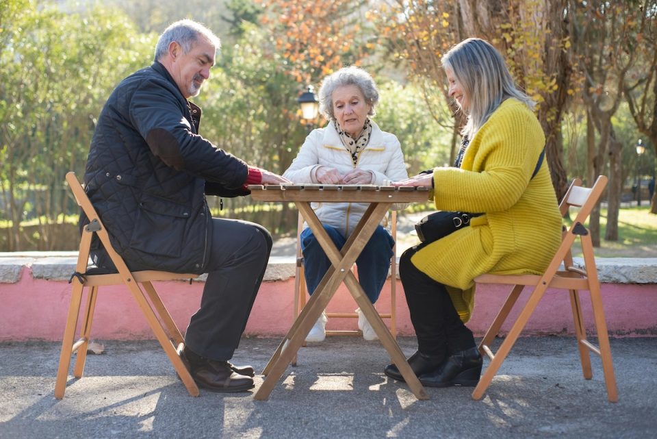 Three people playing a game on an outdoor table. (Kampus Production/Pexels)
