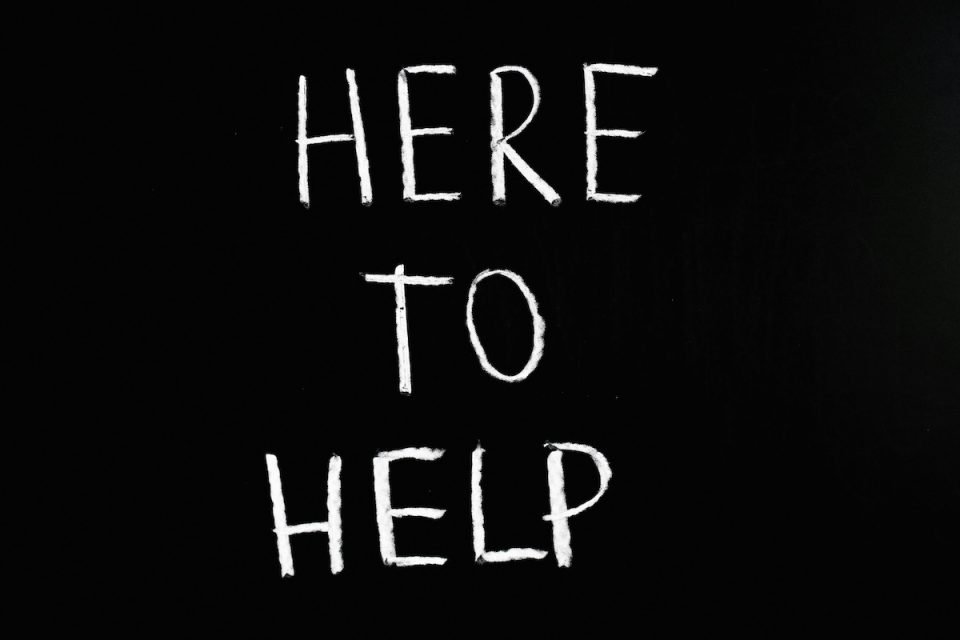 White writing on a black background that reads "Here to help." (Anna Tarazevich/Pexels)