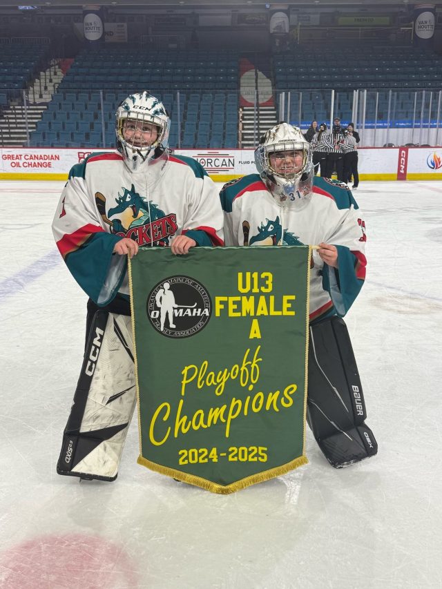 Chloe on the left with her goalie partner holding their playoff championship banner 