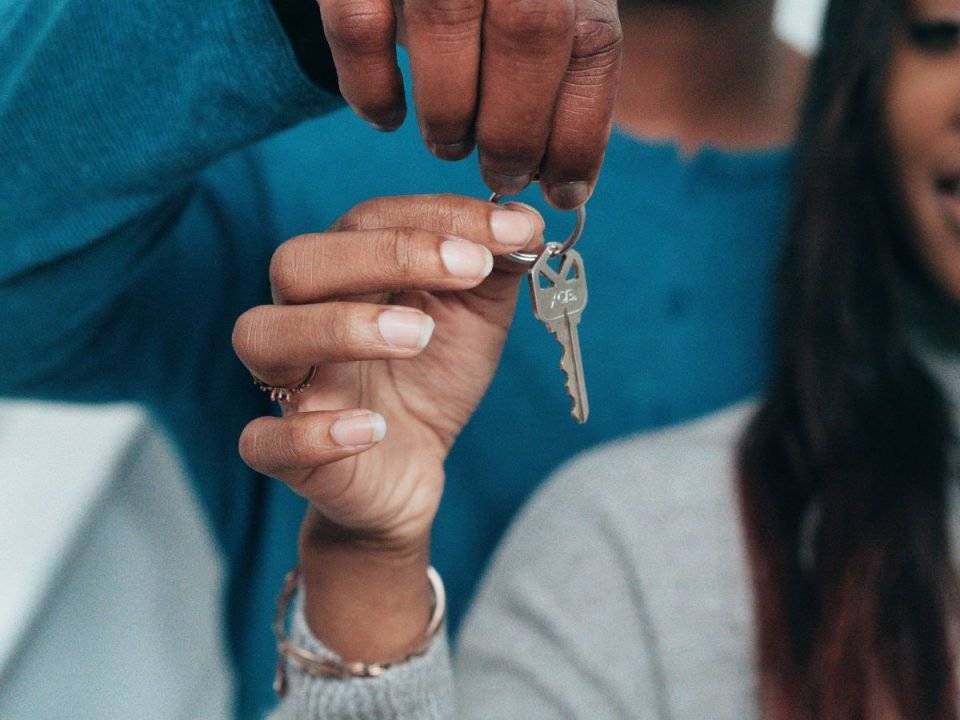 One person handing a key to another person by hand. Their faces are not shown. (Kindel Media/Pexels)